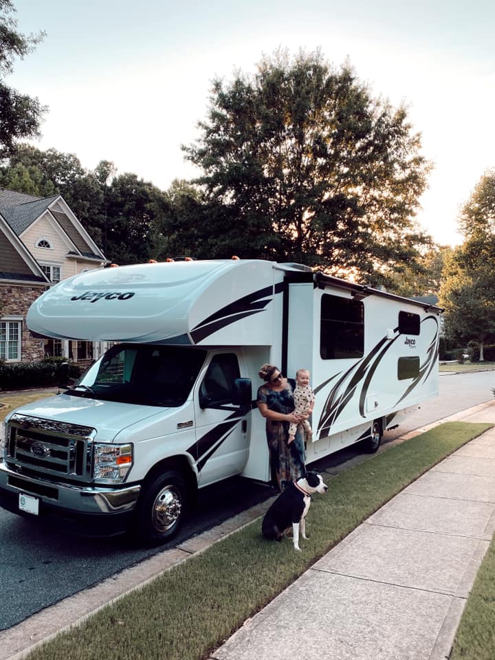 Ady Meschke in front of her Class C RV with her dog and baby