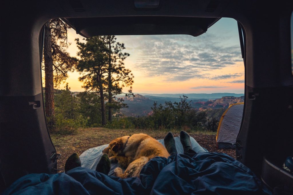 Enjoying sunrise while car camping over a cliff in Sedona, Arizona with girl and dog
